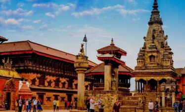 People walking through Bhaktapur Durbar Square surrounded by historic temples and traditional architecture