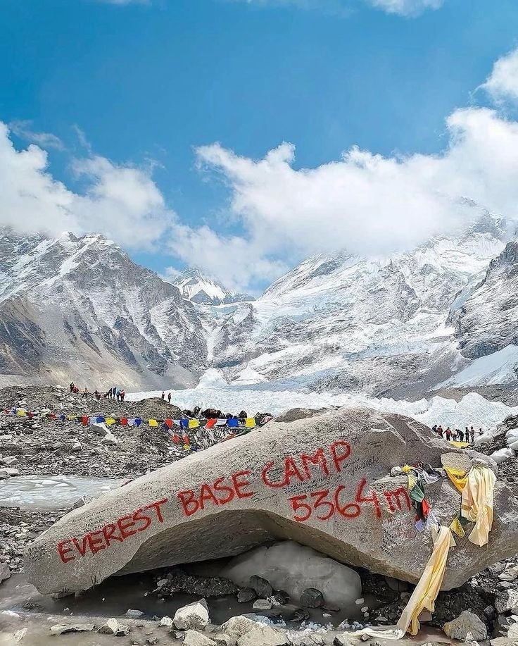 "Everest Base Camp marker rock at 5,364m with snow peaks and prayer flags"